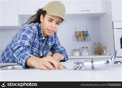 young female plumber working on sink