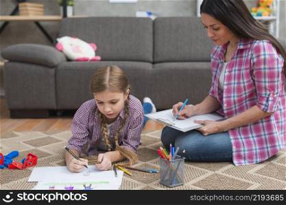 young female psychologist taking notes while girl drawing white paper
