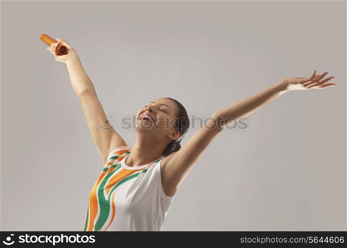 Young female relay runner celebrating victory isolated over gray background