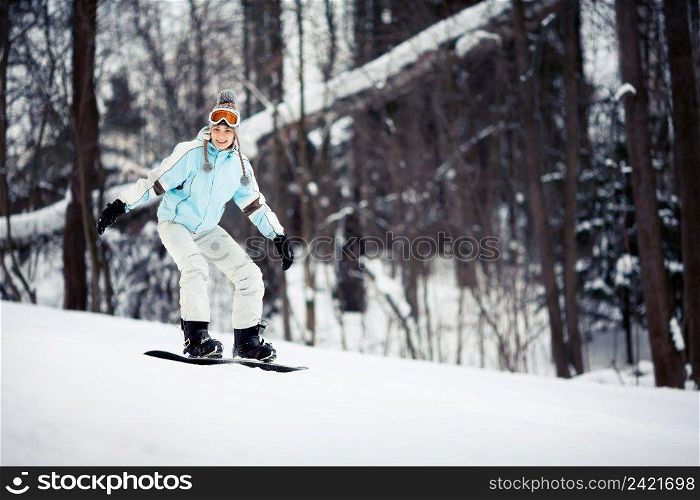 Young female snowboarder sliding down the slope, copy space