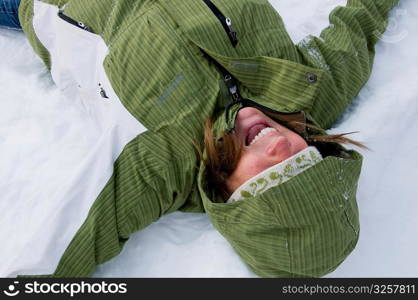 Young female student playing and making winter snow angels.