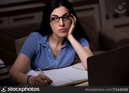 Young female student preparing for exams at night time 