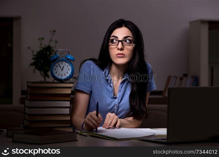 Young female student preparing for exams at night time 