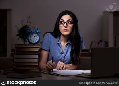 Young female student preparing for exams at night time 