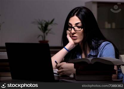 Young female student preparing for exams at night time 