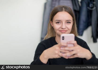 young female student using a mobile phone during the break in the classroom