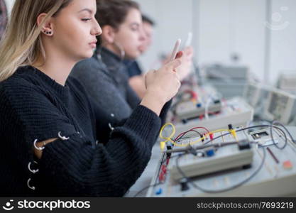 young female student using a mobile phone during the break in the electronics classroom