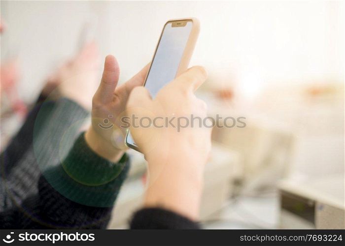 young female student using a mobile phone during the break in the electronics classroom