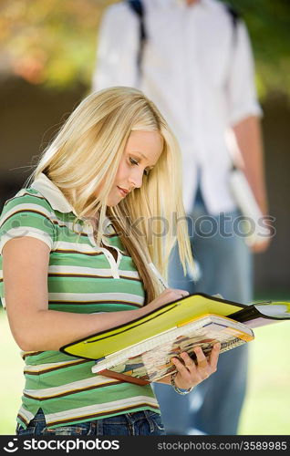 Young female student writing in notebook