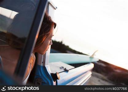 Young female surfer looking from pick up truck window, Leucadia, California, USA