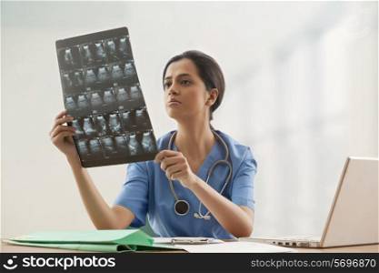 Young female surgeon analyzing ultrasound report at desk
