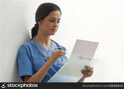 Young female surgeon reading documents isolated over white background