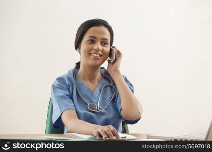 Young female surgeon using cell phone at desk