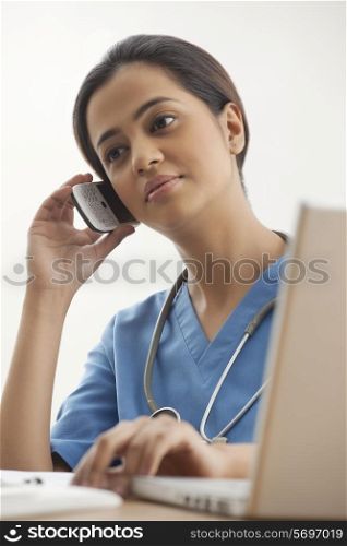 Young female surgeon using mobile phone at desk