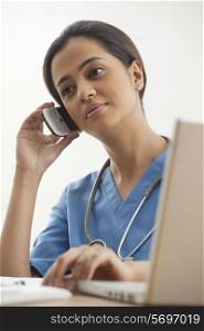 Young female surgeon using mobile phone at desk