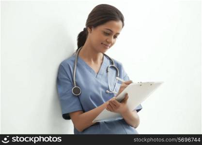 Young female surgeon writing notes isolated over white background