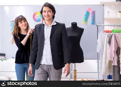 Young female tailor taking measurements for formal suit