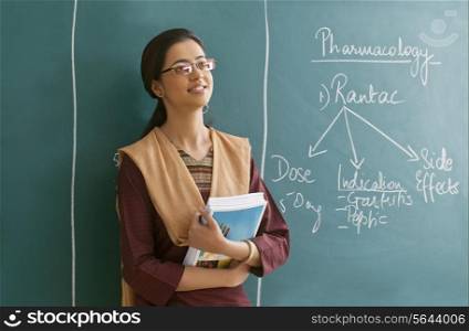 Young female teacher contemplating while leaning on chalkboard