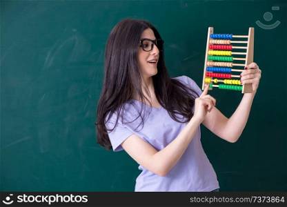 Young female teacher student in front of green board 