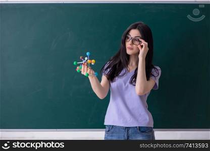 Young female teacher student in front of green board 