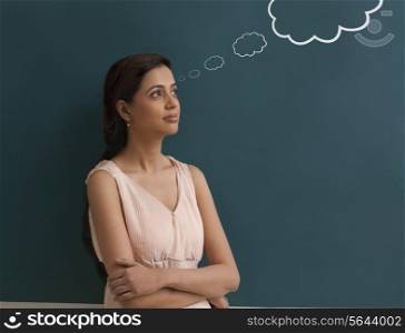 Young female teacher with thought bubble on chalk board