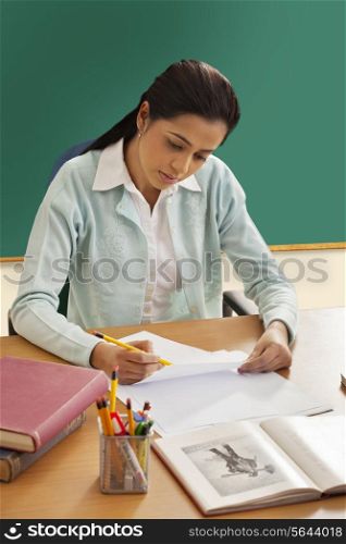 Young female teacher writing on paper