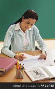 Young female teacher writing on paper