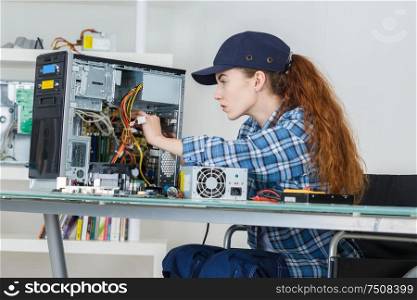 young female tech tests electronic equipment in service centre