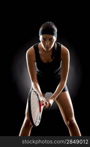 Young female tennis player ready to play on black background
