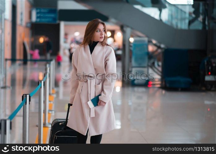 Young female traveller walking the airport hall draging suitcase. Traveller walking the airport hall.