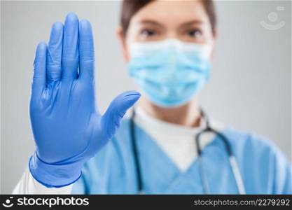 Young female UK NHS ICU doctor hand gesturing STOP Coronavirus COVID-19 disease global pandemic outbreak,please help not spread virus worldwide,stay safe home keep social physical distance isolation