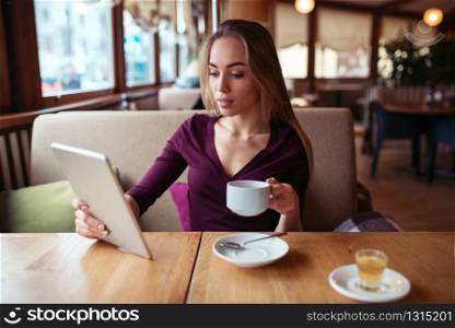 Young female using wifi on tablet pc and drink coffee in cafe.