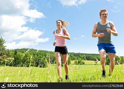 Young fit couple jogging on summer day in meadows countryside