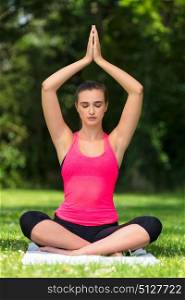 Young fit healthy woman female or girl practicing yoga pose on a mat outside in a natural tranquil green environment