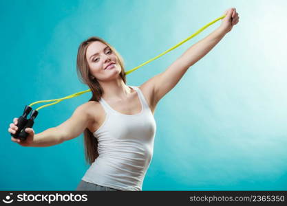 Young fit slim woman spend actively free time. Beauty happy girl wearing sports clothes with jumping skipping rope on blue background.. Fit woman with jumping rope
