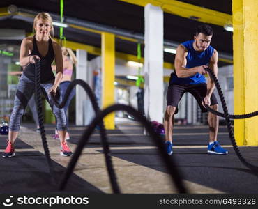 young fit sports couple working out in functional training gym doing crossfitness exercise with battle ropes. sports couple doing battle ropes crossfitness exercise