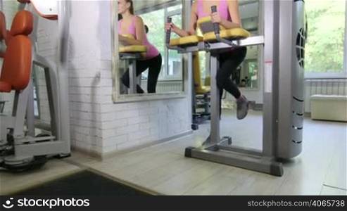 Young fit woman doing hamstrings exercise on standing leg curl machine in fitness club, jib crane shot