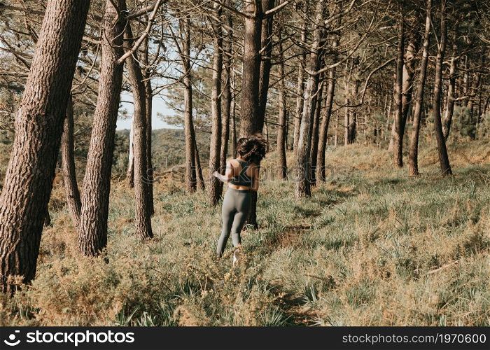 Young fit woman doing jogging in the forest during a spring sunny day with copy space