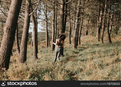 Young fit woman doing jogging in the forest during a spring sunny day with copy space