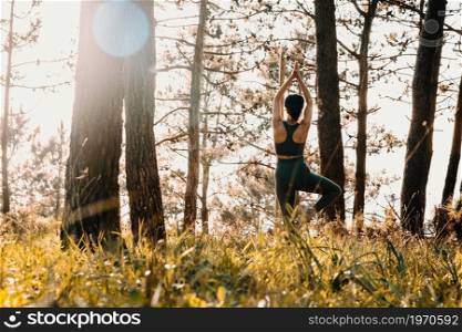 Young fit woman doing yoga in the forest during a spring sunny day with copy space relax concept