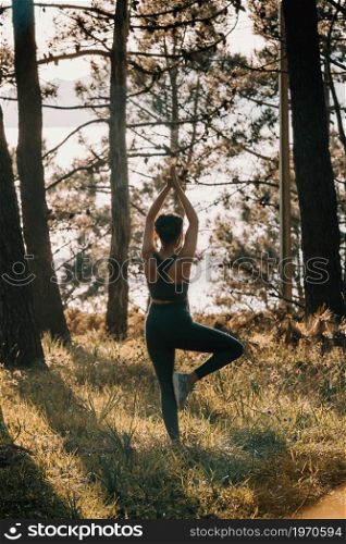 Young fit woman doing yoga in the forest during a spring sunny day with copy space relax concept