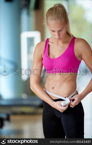 young fit woman measuring belly on a training in fitness gym