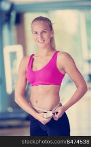 young fit woman measuring belly on a training in fitness gym. young fit woman measuring belly