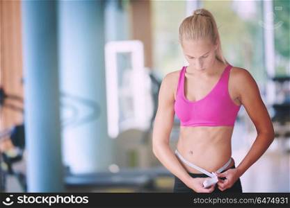 young fit woman measuring belly on a training in fitness gym. young fit woman measuring belly