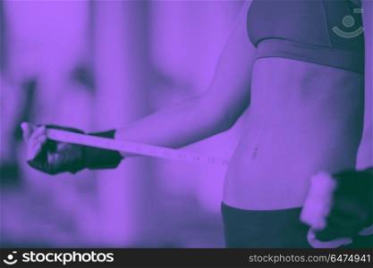 young fit woman measuring belly on a training in fitness gym duo tone. young fit woman measuring belly
