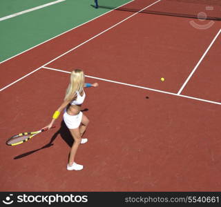 young fit woman play tennis outdoor on orange tennis field at early morning