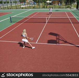 young fit woman play tennis outdoor on orange tennis field at early morning