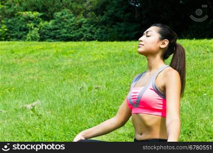Young fit woman practices yoga in the park to meditate and relax