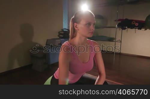 Young fit woman with light dumbbells exercising on fitness ball jib crane shot