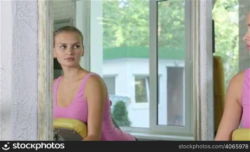 Young fit woman working out on standing leg curl machine in fitness club pan shot